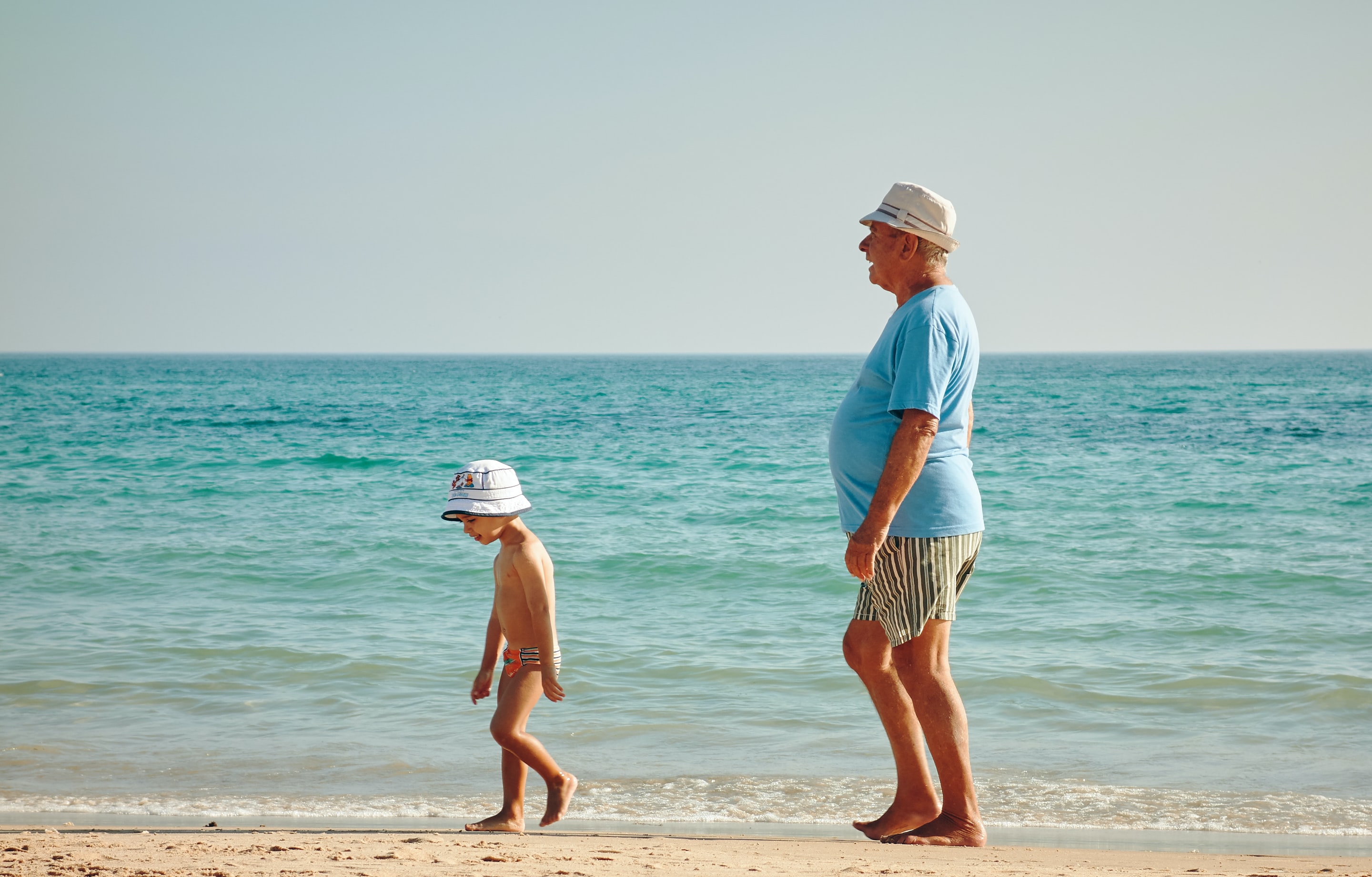 nieto y abuelo paseando por la playa