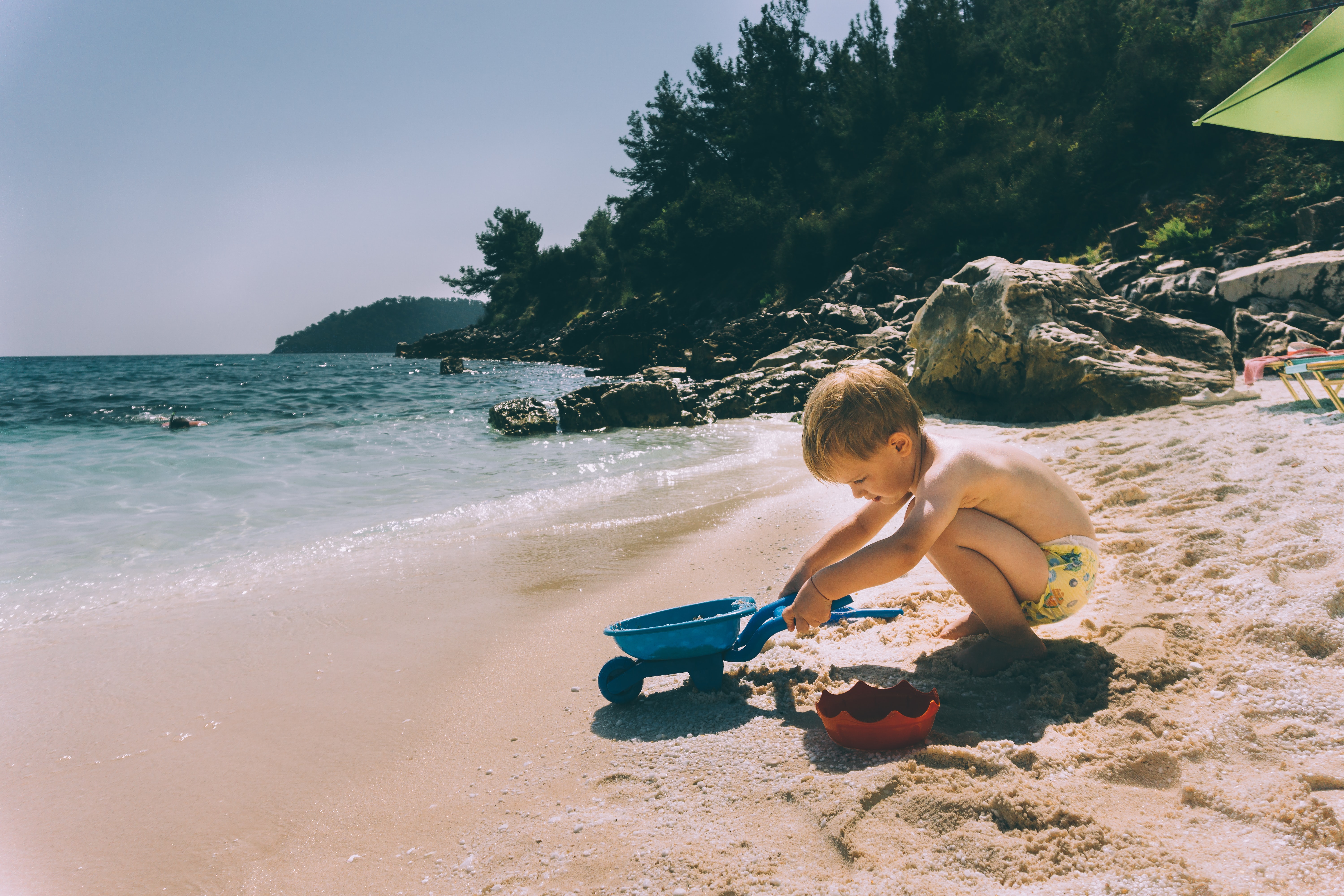 niño jugando con juguetes de playa en la orilla
