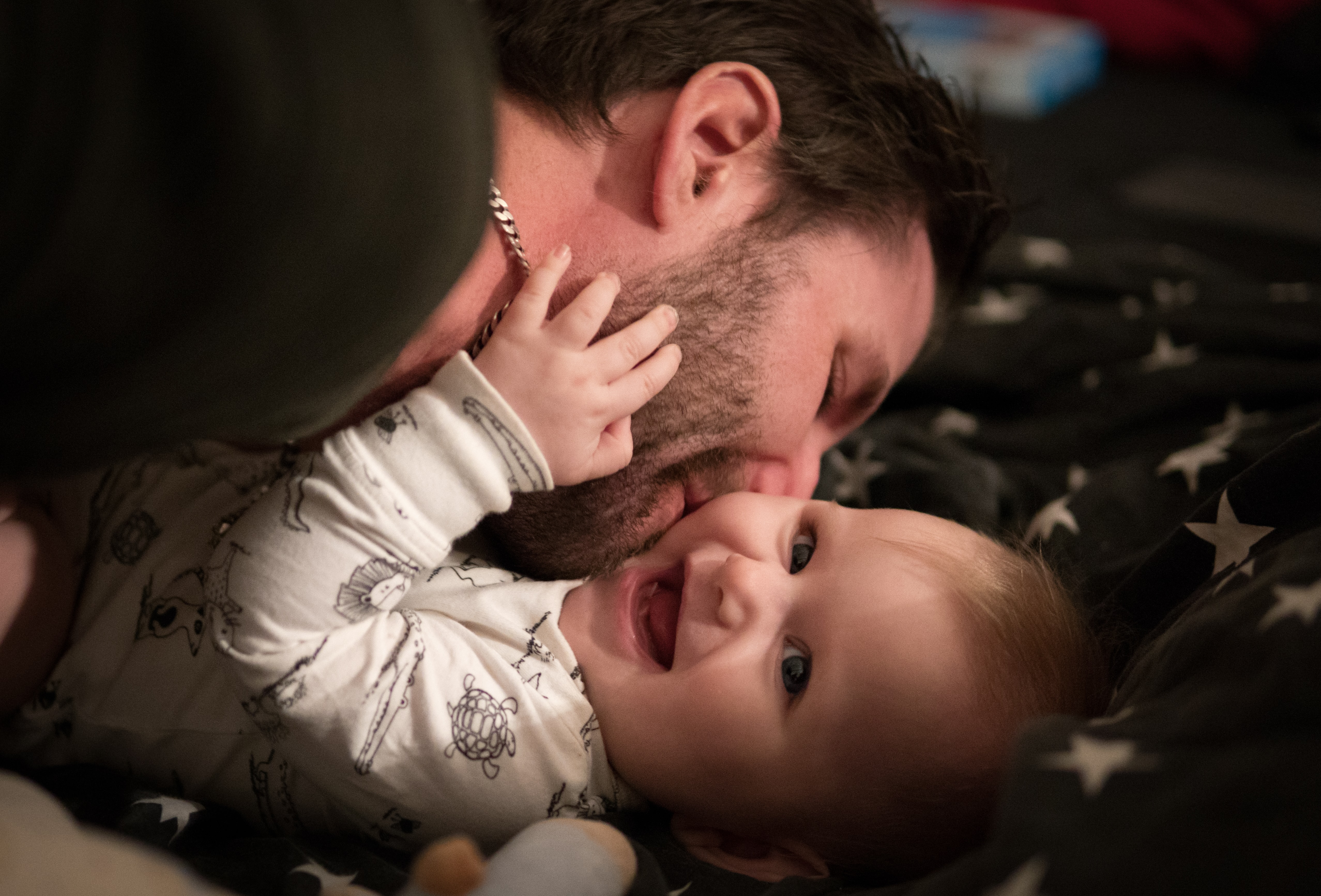papá besando en la mejilla a su bebé mientras éste ríe
